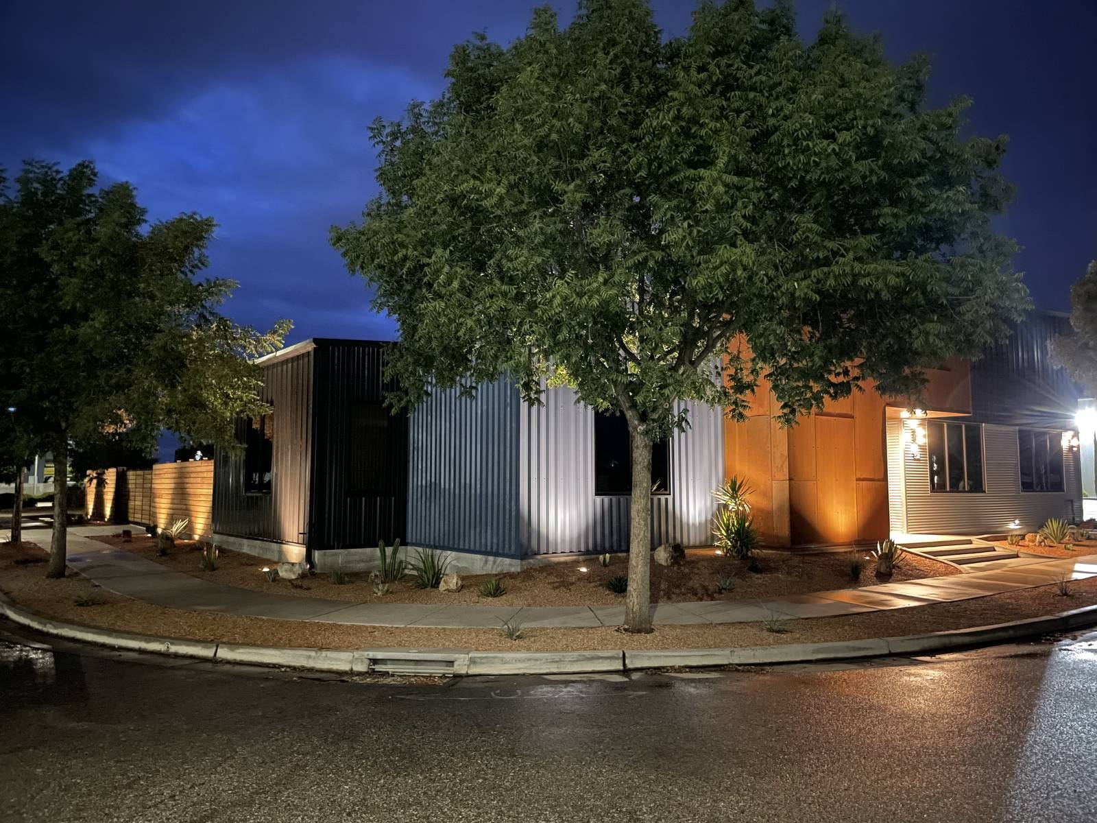 Modern metal-sided building with landscape lighting by Capps Construction