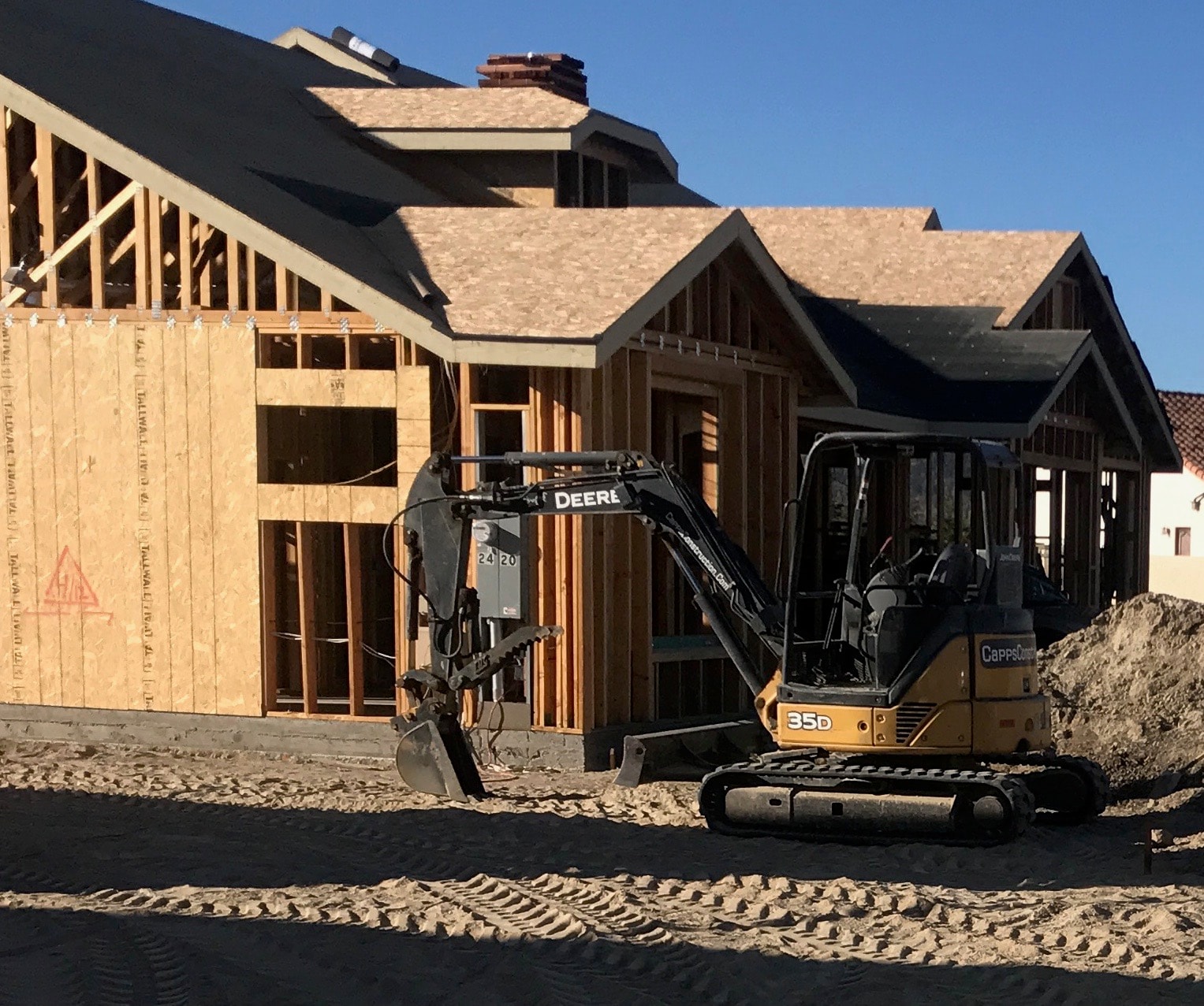 Residential home addition framing with Capps Construction excavator on site